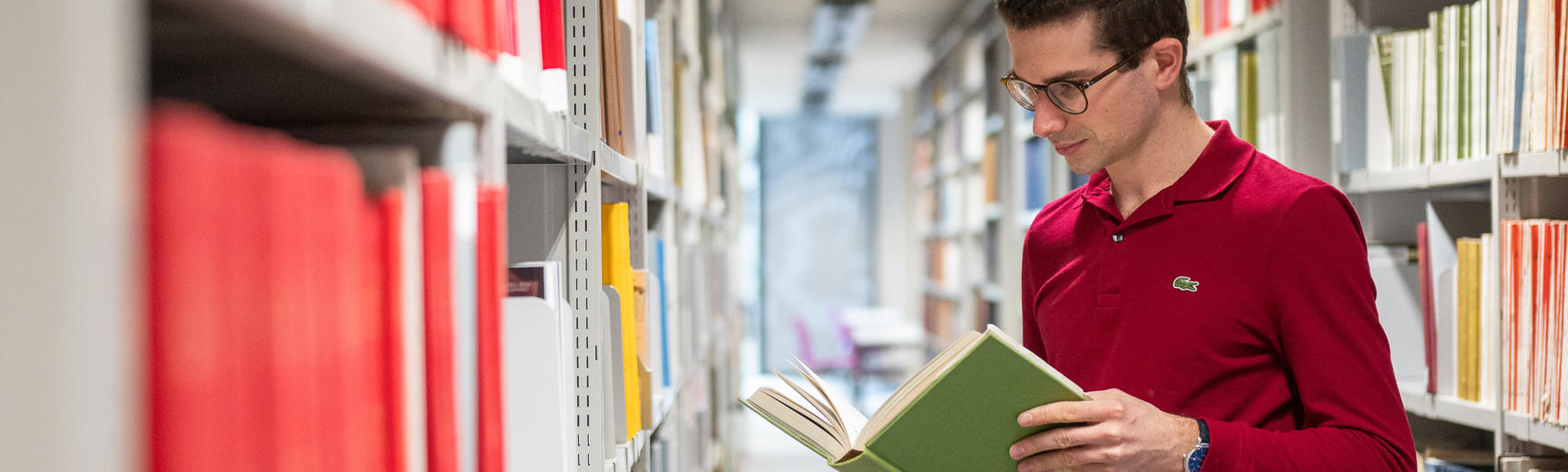 student looks at book in library