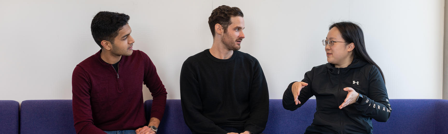 Three members of the Department sitting on a sofa talking