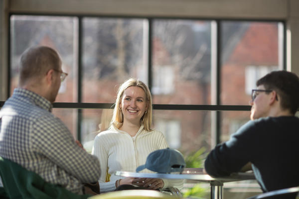 Three MPhil students chatting at a table