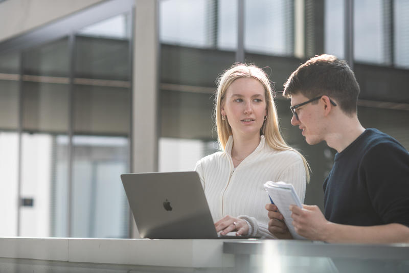 two students speak in manor road atrium